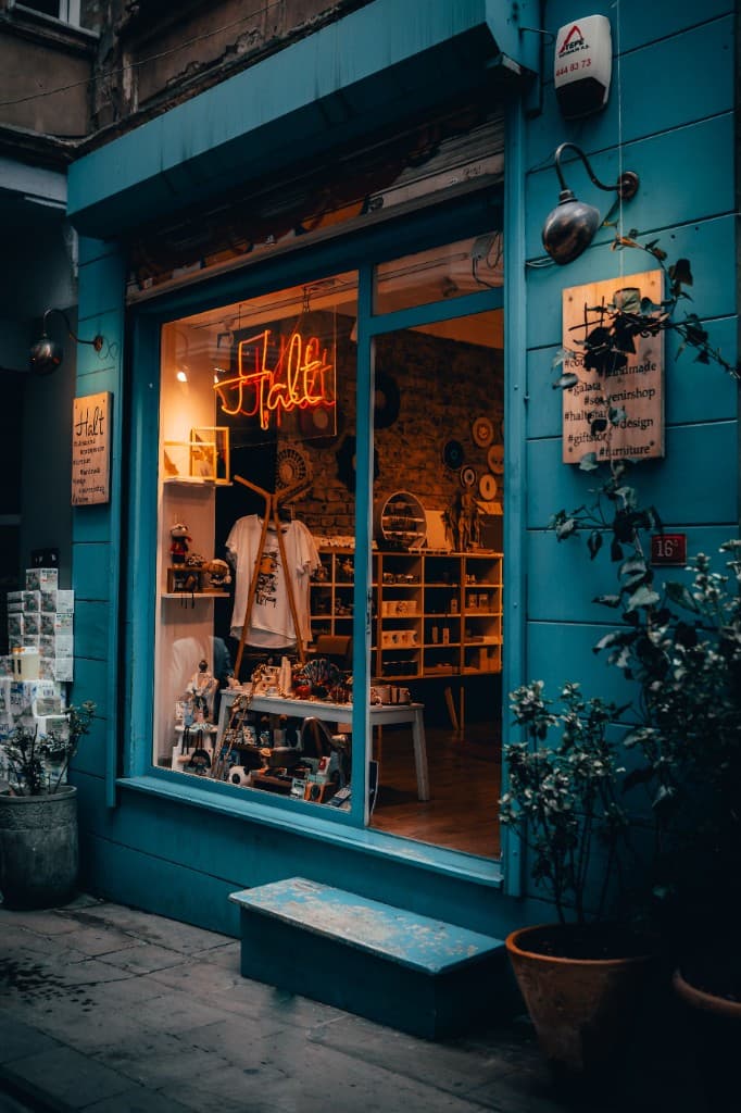A blue neighborhood shopfront with a neon sign in the window